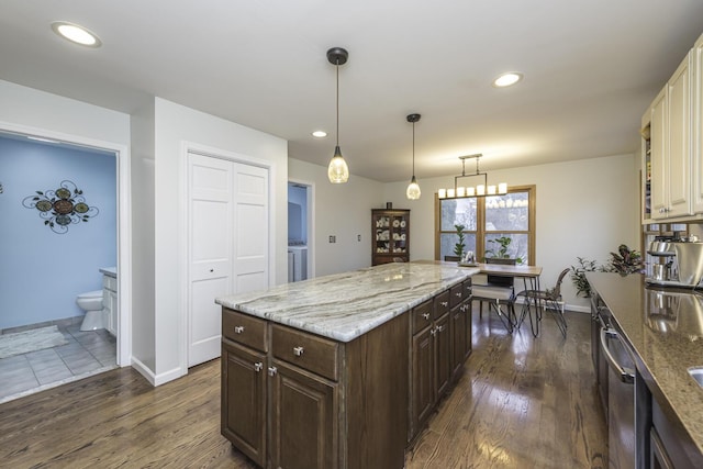 kitchen featuring pendant lighting, dark wood finished floors, dark brown cabinets, and light stone countertops