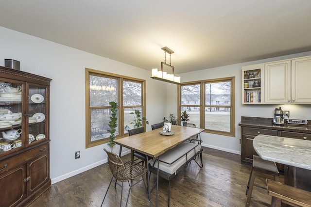 dining room with a chandelier, dark wood finished floors, and baseboards