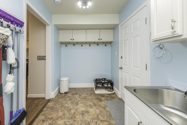 mudroom featuring stone finish floor, baseboards, and a sink