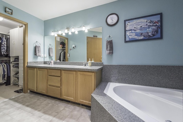 bathroom with double vanity, a walk in closet, and a sink