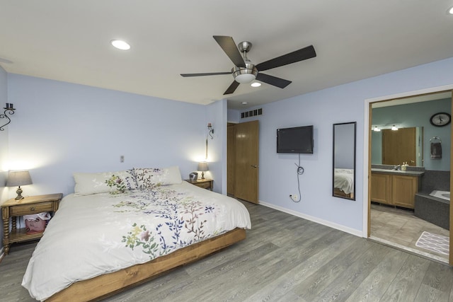 bedroom with baseboards, visible vents, connected bathroom, wood finished floors, and recessed lighting