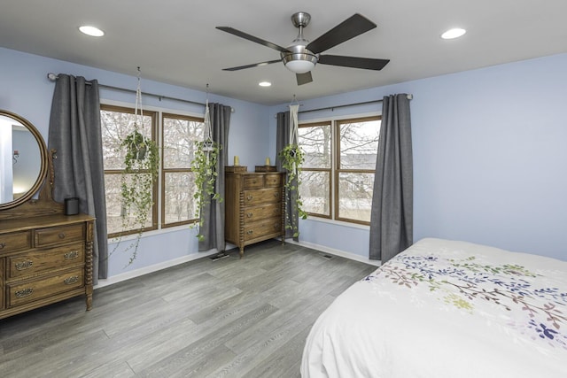 bedroom featuring multiple windows, baseboards, wood finished floors, and recessed lighting