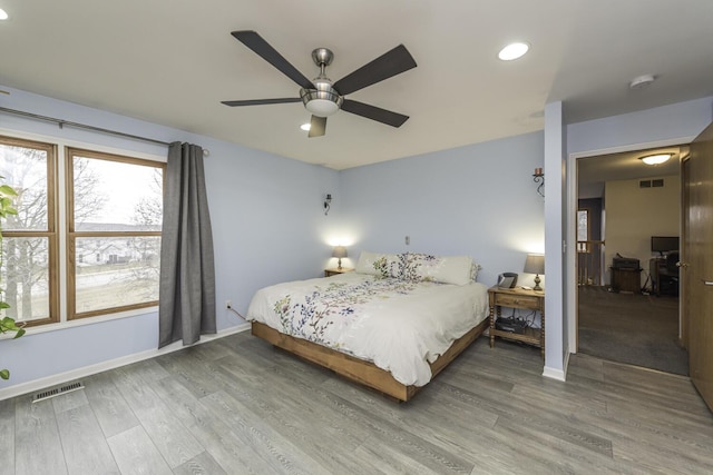 bedroom with baseboards, visible vents, ceiling fan, and wood finished floors