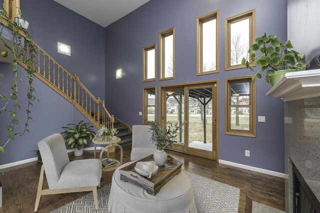 foyer with a towering ceiling, stairway, baseboards, and wood finished floors