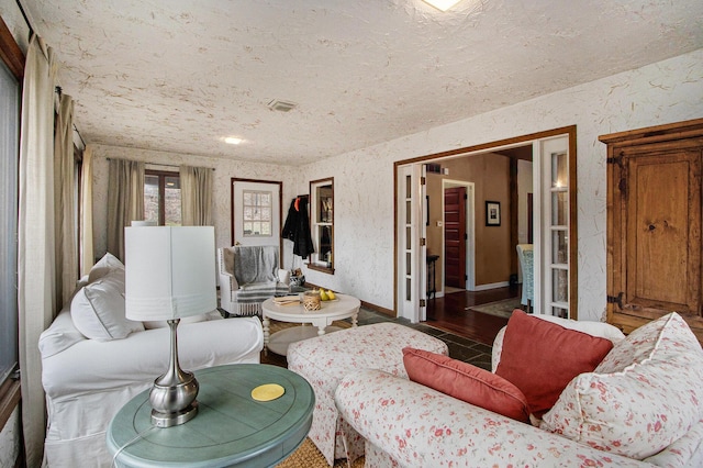 living area featuring visible vents and a textured wall