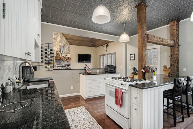 kitchen featuring a peninsula, gas range gas stove, an ornate ceiling, and a sink