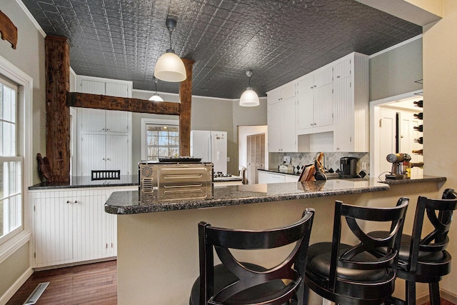 kitchen with an ornate ceiling, tasteful backsplash, a peninsula, and dark wood-type flooring