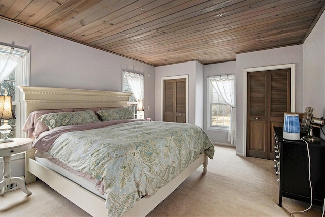 bedroom featuring light colored carpet, two closets, wood ceiling, and crown molding