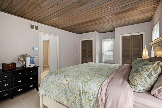 bedroom featuring wooden ceiling, visible vents, two closets, and light carpet