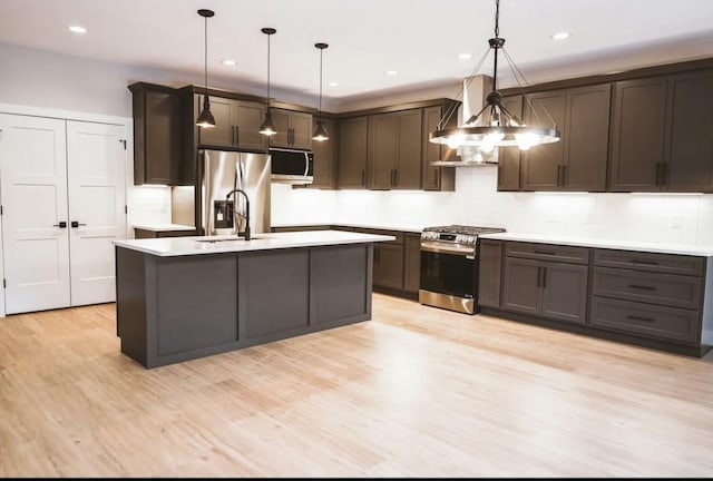 kitchen featuring dark brown cabinetry, appliances with stainless steel finishes, light countertops, light wood-type flooring, and a sink