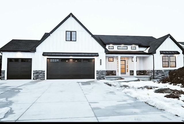 modern farmhouse style home with metal roof, a standing seam roof, stone siding, and board and batten siding