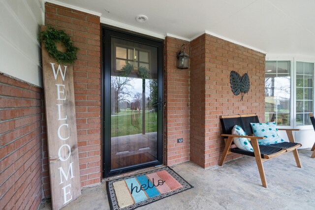 entrance to property with covered porch and brick siding