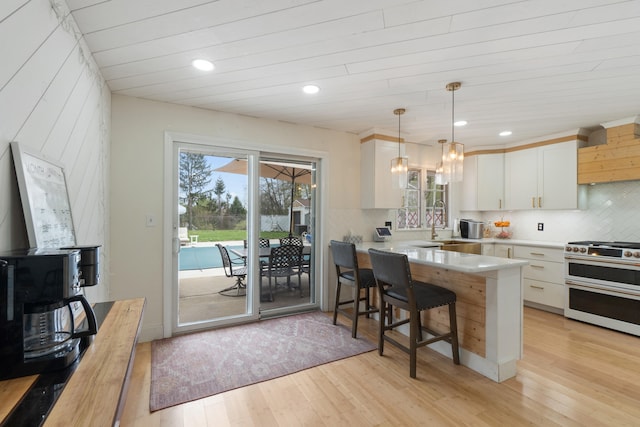 kitchen with range with two ovens, a wealth of natural light, and light wood-style floors