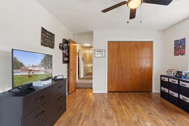bedroom with baseboards, a ceiling fan, light wood-style floors, and a closet