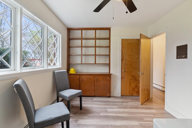 living area featuring a ceiling fan, baseboard heating, and light wood-type flooring