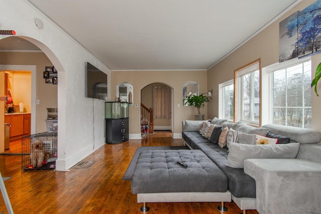 living room with arched walkways, baseboards, stairs, hardwood / wood-style floors, and crown molding