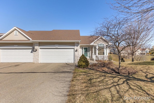 view of front of property with brick siding, a garage, aphalt driveway, and a front lawn