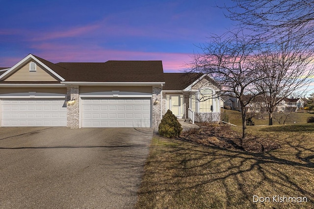 view of front facade featuring aphalt driveway, a garage, brick siding, and roof with shingles