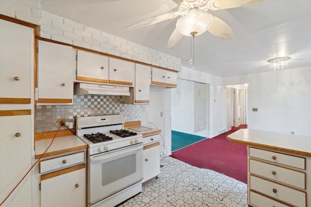 kitchen featuring tasteful backsplash, white gas range oven, ceiling fan, light countertops, and under cabinet range hood