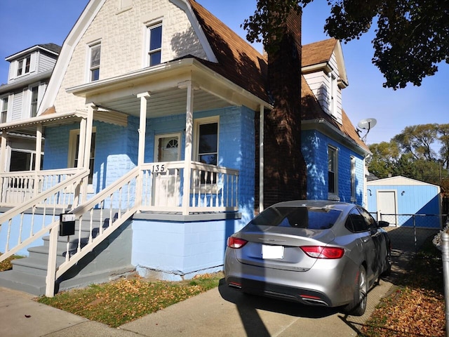 view of front facade with covered porch and a gambrel roof