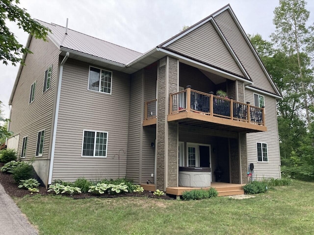 back of house featuring metal roof, a lawn, and a wooden deck