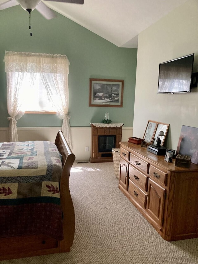 bedroom featuring light colored carpet, vaulted ceiling, a fireplace, and ceiling fan