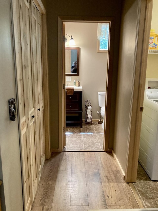 hallway featuring light wood-type flooring, washer / clothes dryer, and baseboards