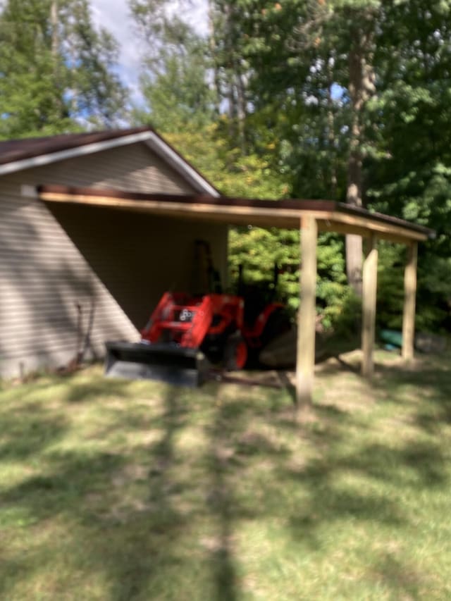 view of side of home featuring driveway, a carport, and a yard