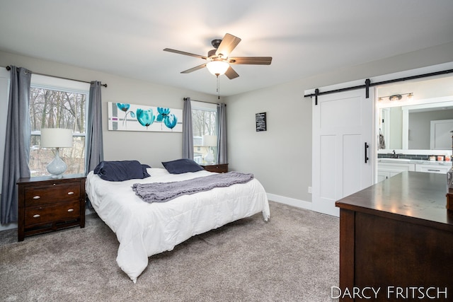 carpeted bedroom featuring a barn door, multiple windows, a sink, and connected bathroom