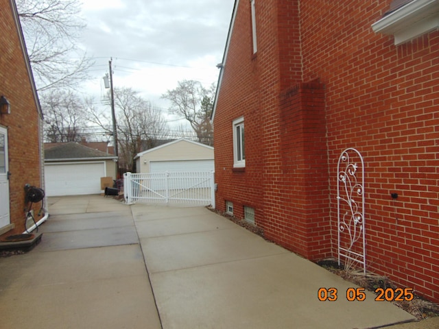 view of side of home with a garage, brick siding, and an outbuilding