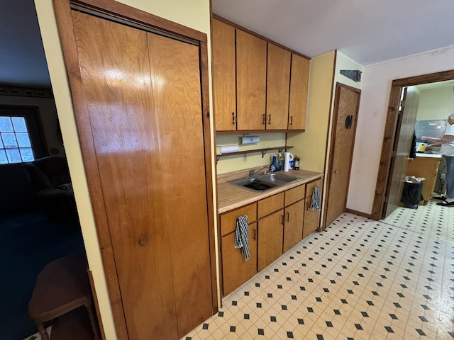 kitchen featuring light countertops, brown cabinetry, a sink, and light floors