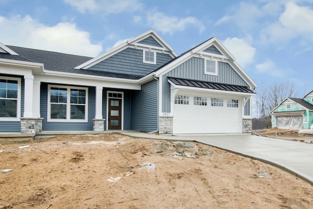 view of front facade with a standing seam roof, metal roof, a garage, stone siding, and driveway