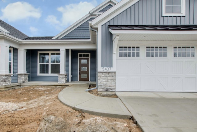 view of front facade with an attached garage, stone siding, concrete driveway, board and batten siding, and a standing seam roof