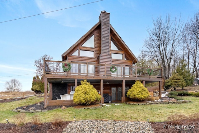 back of house with a lawn, a chimney, and a wooden deck