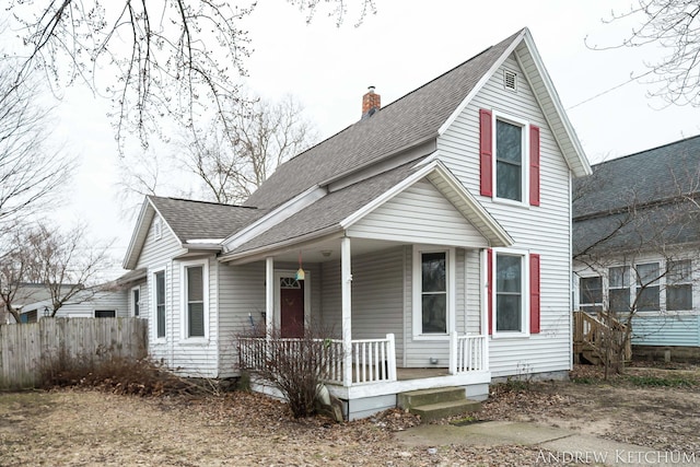 view of front of property featuring a chimney, fence, a porch, and roof with shingles