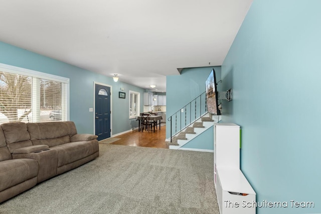 carpeted living room featuring baseboards and stairway