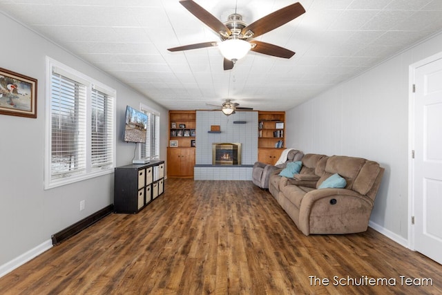 living area featuring a large fireplace, baseboards, built in features, and wood finished floors