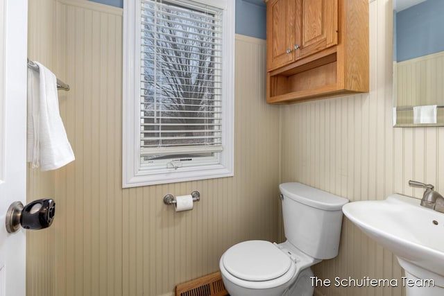 half bath with toilet, visible vents, and a sink