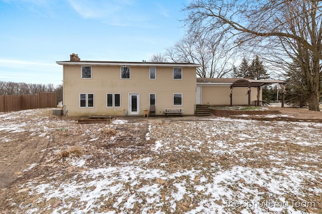 snow covered property featuring entry steps, a chimney, and fence