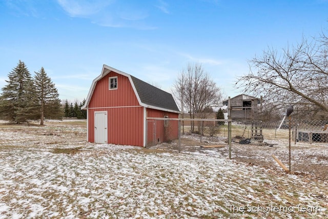 snow covered structure featuring a barn, fence, and an outdoor structure