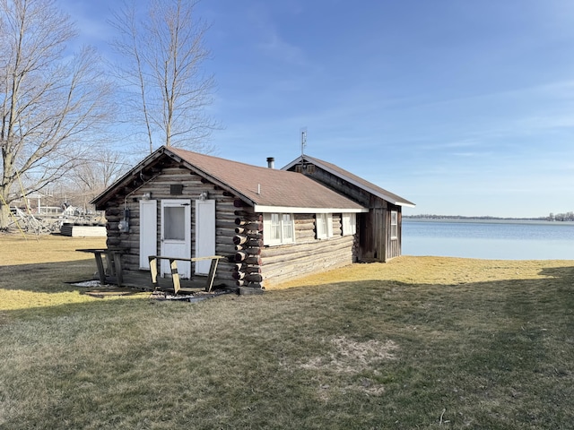 view of side of home featuring a lawn, log exterior, and a water view