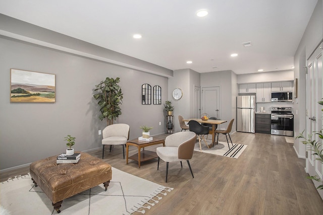 living room featuring recessed lighting, baseboards, and wood finished floors