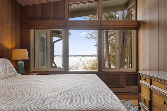 bedroom with a baseboard radiator, wooden walls, and multiple windows