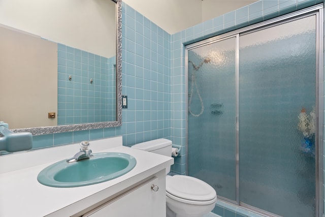 bathroom featuring vanity, a shower stall, toilet, and tile walls