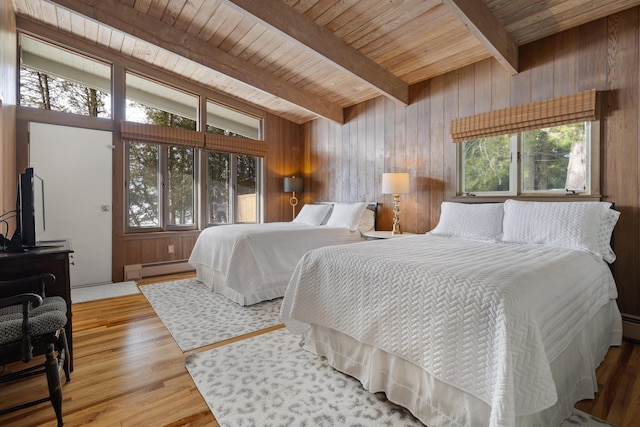 bedroom featuring multiple windows, beamed ceiling, baseboard heating, and wood finished floors