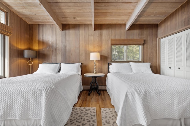 bedroom featuring wooden ceiling, beamed ceiling, wood walls, and wood finished floors