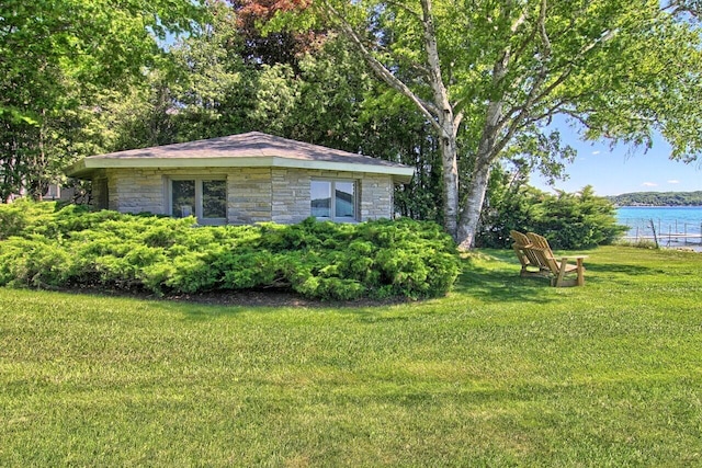 view of side of home with stone siding, a water view, and a yard