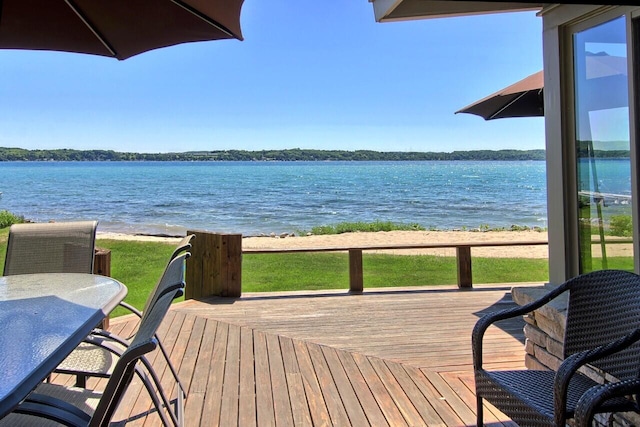 deck with outdoor dining space and a water view