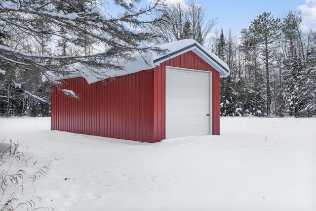 snow covered structure with an outbuilding