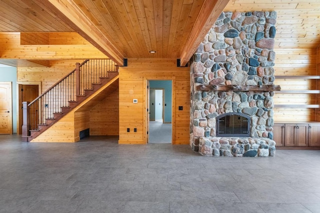 unfurnished living room with wooden ceiling, a fireplace, wood walls, and stairway